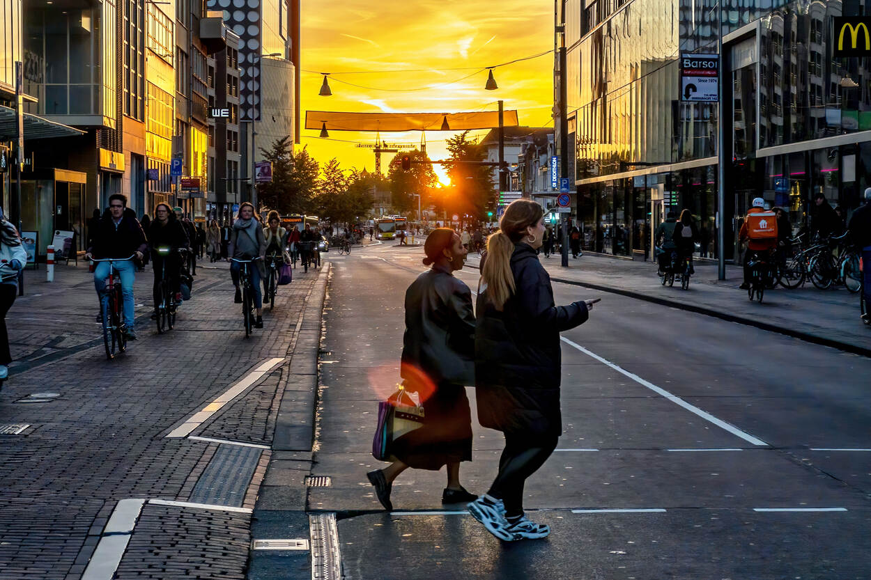 Een drukke straat met voetgangers, fietsers en autoverkeer